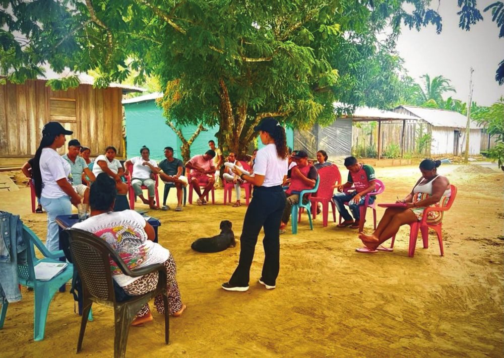 Taller con la comunidad sentada en círculo bajo un árbol